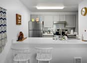 Thumbnail 1 of 27 - A kitchen with a white countertop and stainless steel appliances.