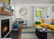 Thumbnail 9 of 27 - A living room with a fireplace and a yellow couch.