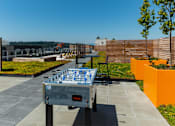 Thumbnail 20 of 26 - a ping pong table on a rooftop patio with a city in the background