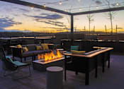 Thumbnail 11 of 26 - a rooftop patio with a fire pit and tables and chairs