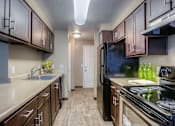 Thumbnail 11 of 16 - A kitchen with brown cabinets and a black refrigerator.
