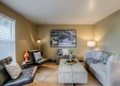 Thumbnail 10 of 16 - A living room with a white couch, a black leather chair, and a coffee table.