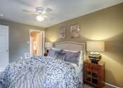Thumbnail 2 of 16 - A bedroom with a bed, nightstand, and a ceiling fan.