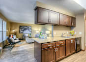 Thumbnail 7 of 16 - A kitchen with wooden cabinets and a countertop with a sink.