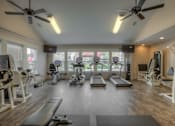 Thumbnail 13 of 16 - A spacious gym with a variety of equipment including treadmills, stationary bikes, and weight machines.