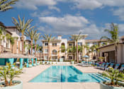 Thumbnail 1 of 21 - A large swimming pool surrounded by palm trees and lounge chairs.