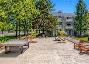Thumbnail 20 of 27 - A concrete patio with a table and chairs in front of a building.