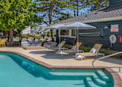 Thumbnail 18 of 27 - A pool with a sun lounger and umbrella next to a building.