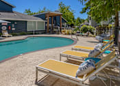 Thumbnail 25 of 27 - A pool with sun loungers and a building in the background.