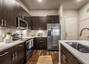 Thumbnail 9 of 24 - A kitchen with dark wood cabinets and stainless steel appliances.