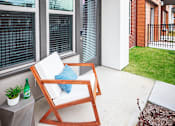 Thumbnail 14 of 24 - A patio with a chair and a table with a bottle on it.