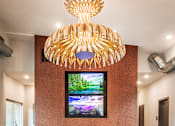 Thumbnail 12 of 24 - A modern living room with a large TV and a unique chandelier.
