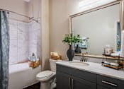 Thumbnail 2 of 24 - A bathroom with a toilet, sink, and a mirror.