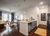 Thumbnail 4 of 24 - A modern kitchen with a white island and stainless steel appliances.
