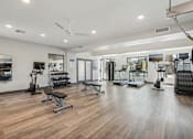 Thumbnail 29 of 33 - a fitness room with weights and cardio equipment on a wooden floor