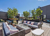 Thumbnail 20 of 41 - a rooftop patio with couches and tables and trees