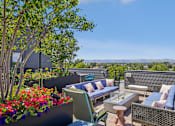 Thumbnail 29 of 41 - a roof deck with couches and chairs and a view of the city