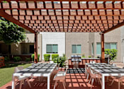 Thumbnail 22 of 24 - A patio with a table and chairs under a wooden pergola.