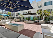 Thumbnail 12 of 15 - A patio with a pool and chairs under a blue umbrella.