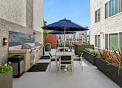 Thumbnail 13 of 15 - A patio with a table and chairs under an umbrella.
