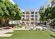 Thumbnail 12 of 24 - A courtyard with a fountain surrounded by trees and apartment buildings.