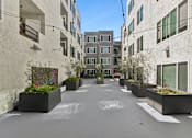 Thumbnail 10 of 15 - A long, narrow courtyard between two buildings with planters on the ends.