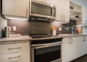 Thumbnail 2 of 24 - a kitchen with white cabinets and a stove and a microwave