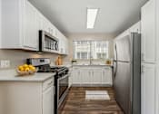 Thumbnail 15 of 24 - a white kitchen with stainless steel appliances and white cabinets