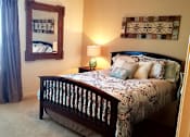 Thumbnail 18 of 19 - A bedroom with a bed, lamp, and picture frame.