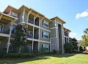 Thumbnail 16 of 19 - A large apartment complex with a green lawn in front.