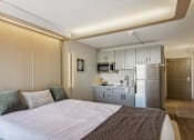 Thumbnail 11 of 26 - a bedroom with a bed and a kitchen with a refrigerator
