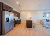 Thumbnail 45 of 53 - a kitchen and living room with stainless steel appliances and a table and chairs
