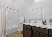Thumbnail 5 of 8 - A bathroom with a white sink, a mirror, and a shower with a curtain.