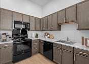 Thumbnail 1 of 8 - A kitchen with black appliances and wooden cabinets.
