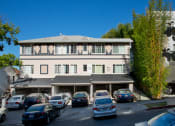 Thumbnail 24 of 64 - Exterior front view of an apartment building with parking spaces