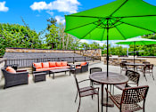Thumbnail 20 of 23 - A patio with a green umbrella and brown furniture.