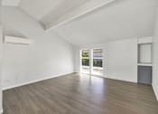 Thumbnail 17 of 33 - A spacious room with wooden flooring and a large window.