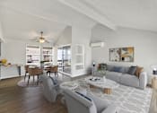 Thumbnail 33 of 33 - A modern living room with a grey sofa, a coffee table, and a dining table set up.