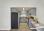 Thumbnail 25 of 33 - A kitchen with a black refrigerator and wooden floors.
