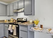 Thumbnail 23 of 33 - A kitchen with a black stove top oven and a marble counter top.