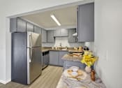 Thumbnail 18 of 33 - A modern kitchen with a stainless steel refrigerator and a table set for two.