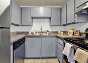 Thumbnail 21 of 33 - A kitchen with a black dishwasher and a black stove top oven.