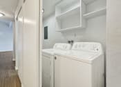 Thumbnail 30 of 33 - A white washing machine and dryer in a small laundry room.