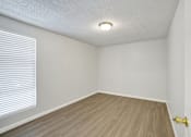 Thumbnail 27 of 33 - A room with a wooden floor and a window with blinds.