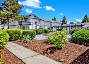Thumbnail 14 of 33 - A white building with a black roof and a garden in front.