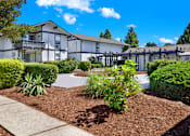 Thumbnail 1 of 33 - A white building with a black roof and a green bush in front.