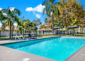 Thumbnail 9 of 31 - Outdoor swimming pool with lounge chairs and umbrellas at Coventry Square Apartments, Upland, California