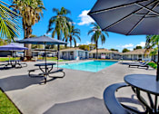 Thumbnail 6 of 31 - Pool deck with shade umbrellas and seating at Coventry Square Apartments, Upland