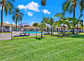 Thumbnail 7 of 31 - Fenced pool area with surrounding green lawn at Coventry Square Apartments, Upland, CA 97186