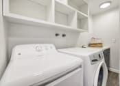 Thumbnail 29 of 33 - A white washing machine and dryer in a laundry room.